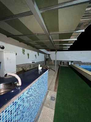 A poolside area with a blue-tiled counter, a white refrigerator, and a view of the sea. - CT 355 AL - Faro's Pechina Rural (Pechina)