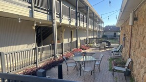 Une cour avec des sièges en plein air, un mur en pierre et un bâtiment doté de balcons.
