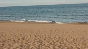 Ein Strand mit sandigem Ufer und ruhigen Wellen.