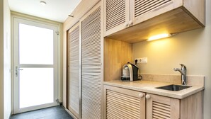 Et lille køkken med indbygget vask, kaffemaskine og en lampe over bordpladen.