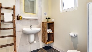 Un baño con una escalera de madera, lavamanos blanco y retrete.