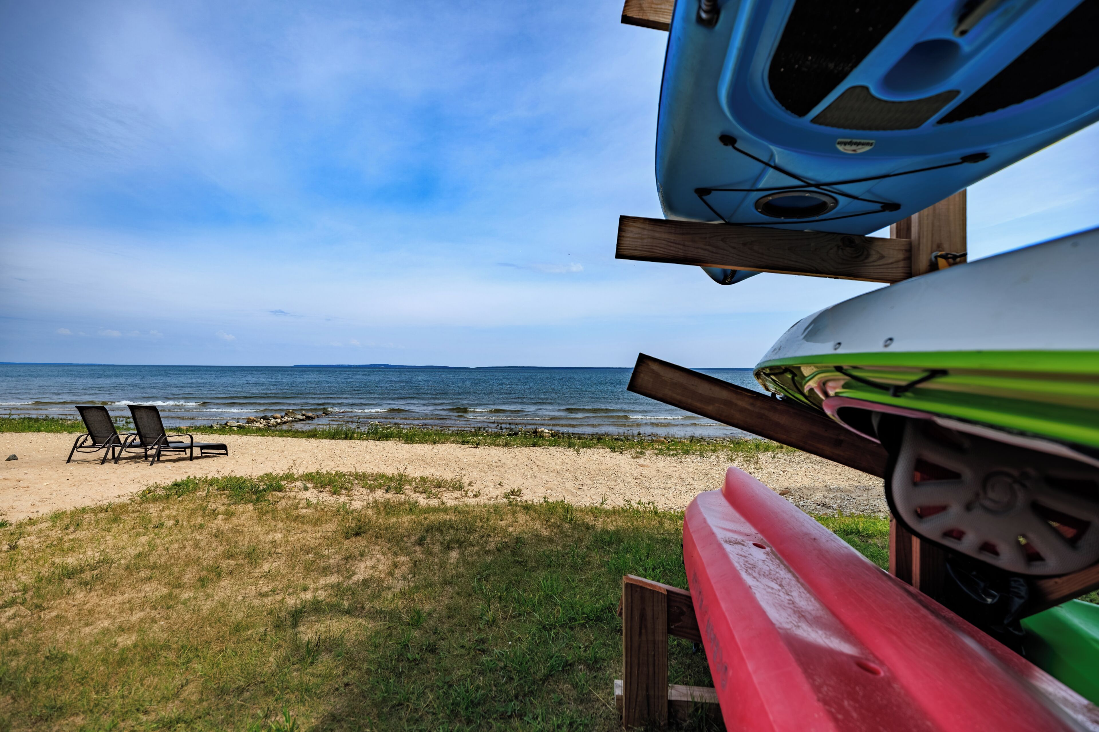 A beach with two lounge chairs and kayaks.