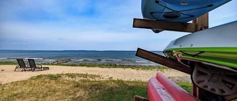 A beach with two lounge chairs and kayaks.