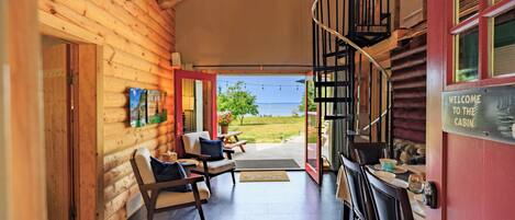 A cabin interior with a wooden exterior, a spiral staircase, and a view of the outdoors.