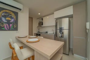 Een moderne keuken met een centraal eiland, roestvrijstalen apparatuur en een magnetron boven het aanrecht.