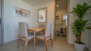 A dining area with a wooden table and four chairs, a potted plant, and two framed artworks on the wall.