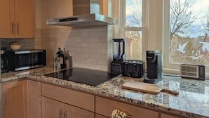 Une cuisine équipée d’une hotte en acier inoxydable, d’un four à micro-ondes, d’un grille-pain et d’une machine à café.
