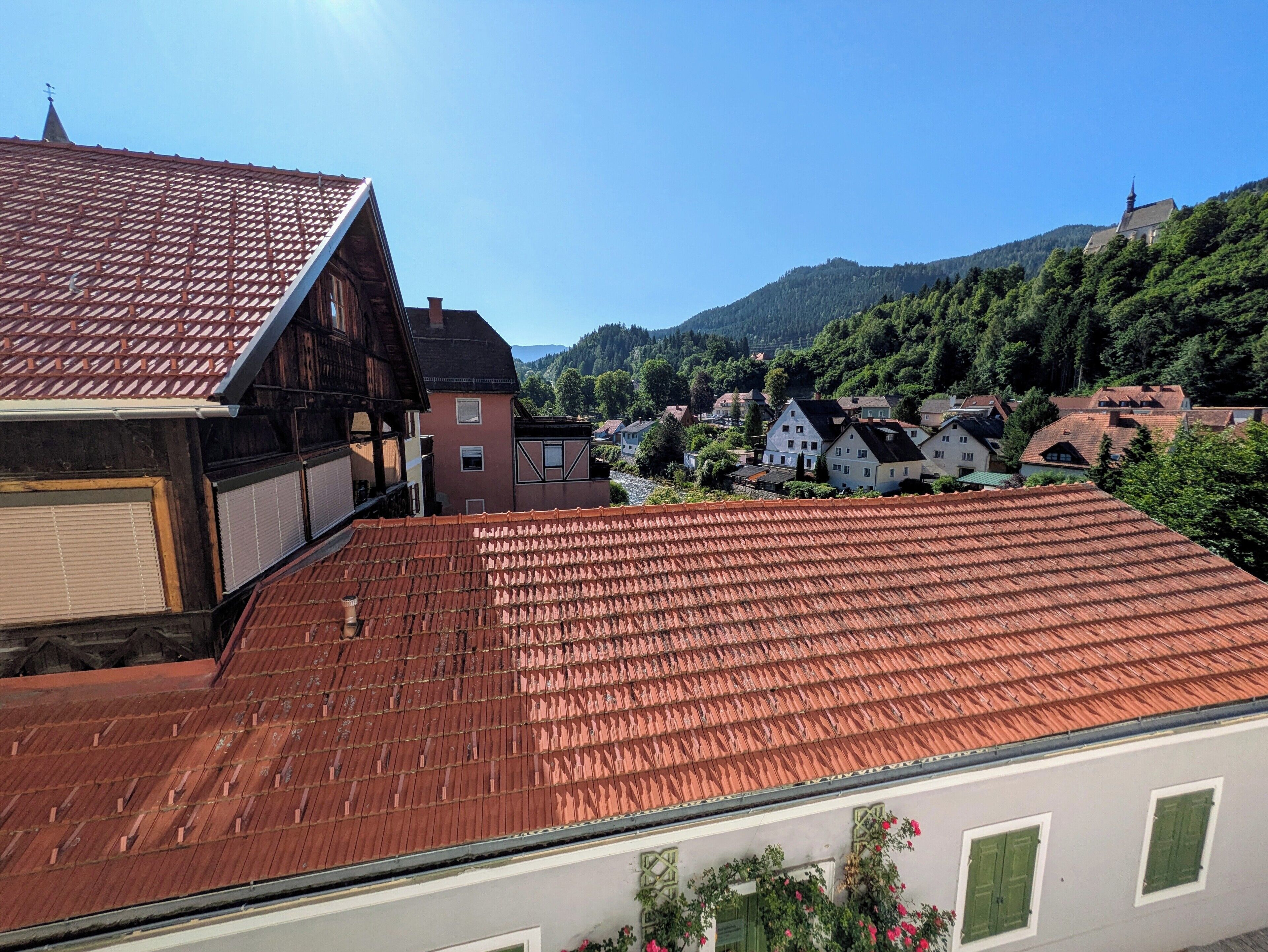 A traditional European village with terracotta roofs, wooden buildings, and lush greenery.