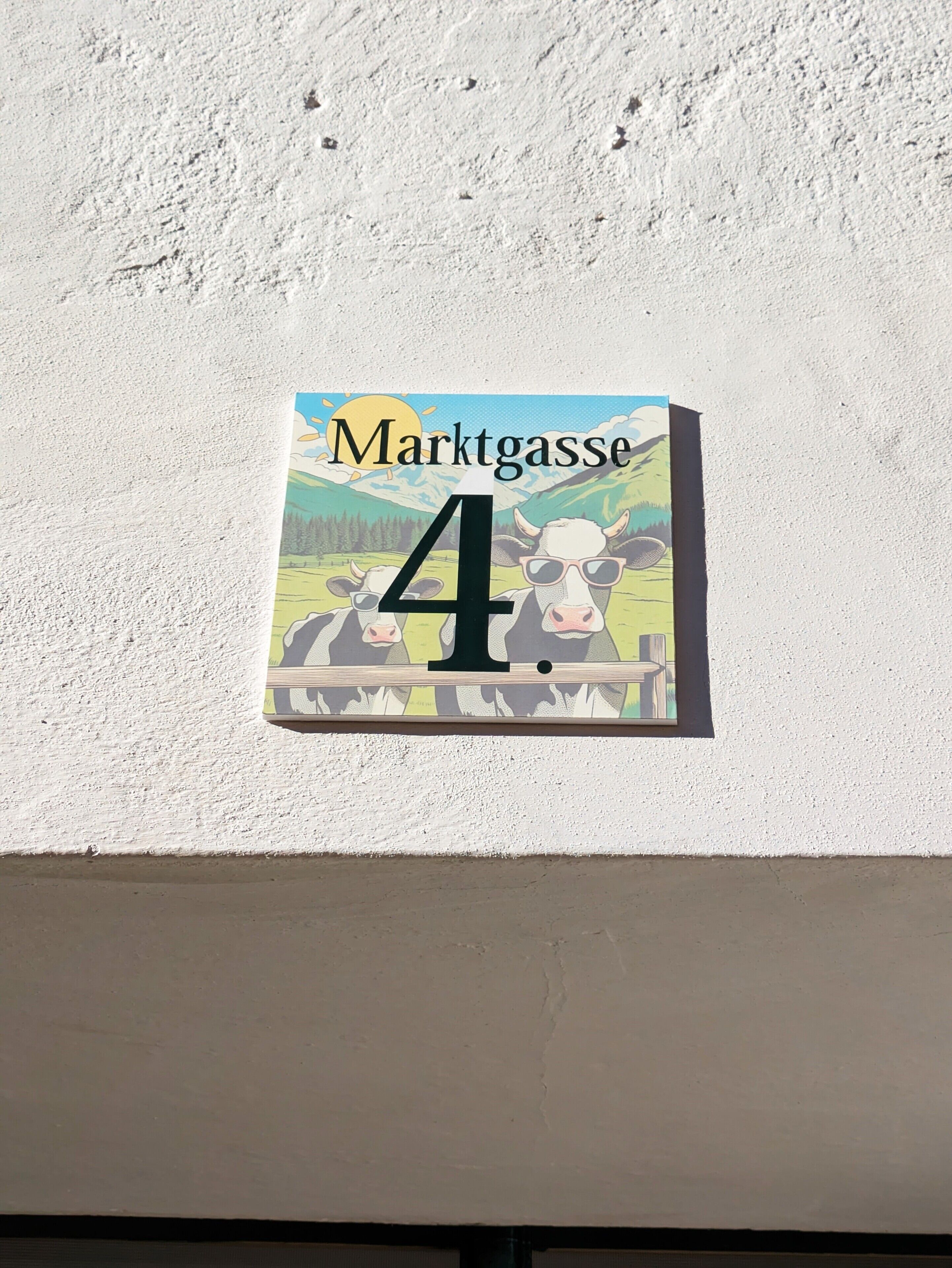 A house number sign with a cow illustration and the text "Marktgasse 4".