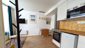 A modern kitchen with a built-in oven, a microwave, and a wooden countertop. There is a dining area with a table and chairs, and a coat rack near the entrance. - mg4 Apartments (Murau)