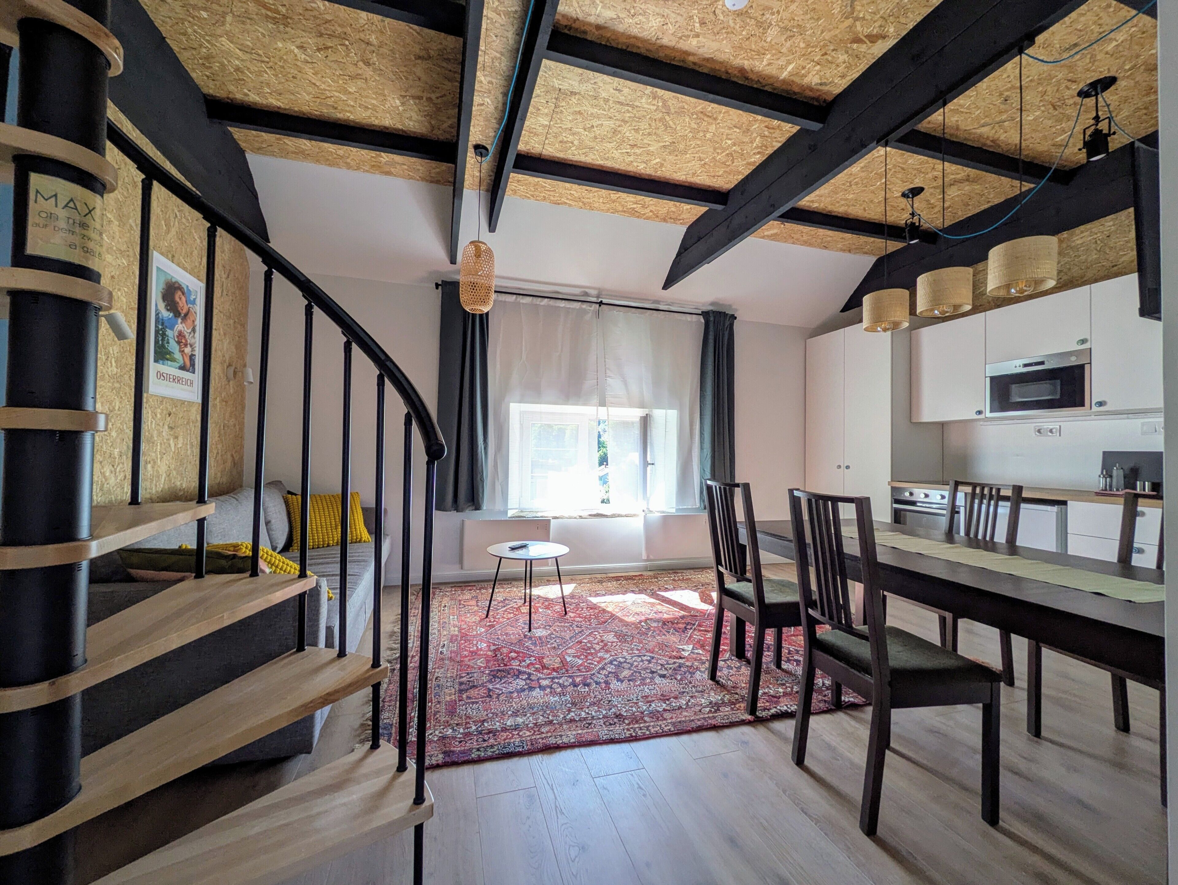 Eine moderne Küche mit Essbereich, einer Holztreppe und Blick ins Freie.