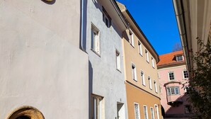 A narrow cobblestone street flanked by historic buildings with multiple windows and a round window on the left. - mg4 Apartments (Murau)
