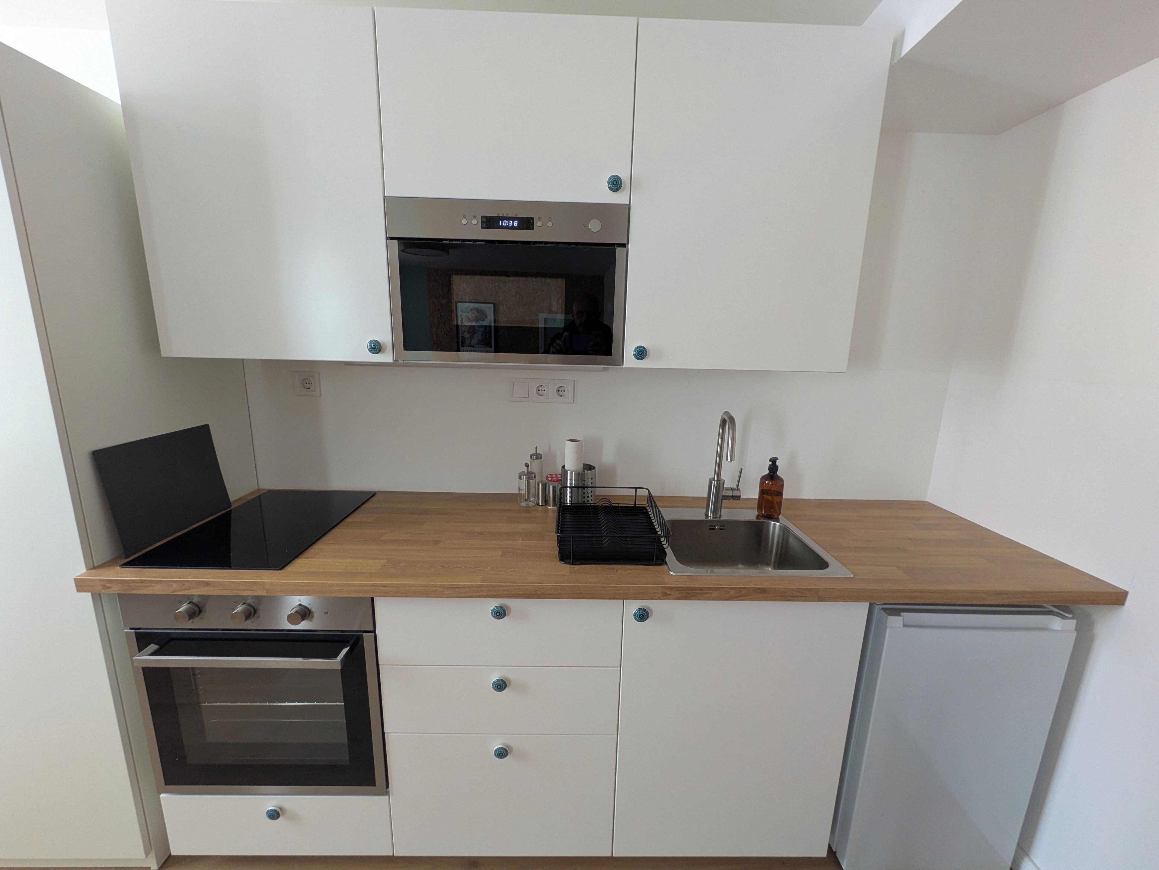 A modern kitchen with a built-in oven, microwave, and stainless steel sink.