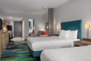 Habitación de hotel con dos camas, un escritorio, una silla, un televisor y un baño a la vista.