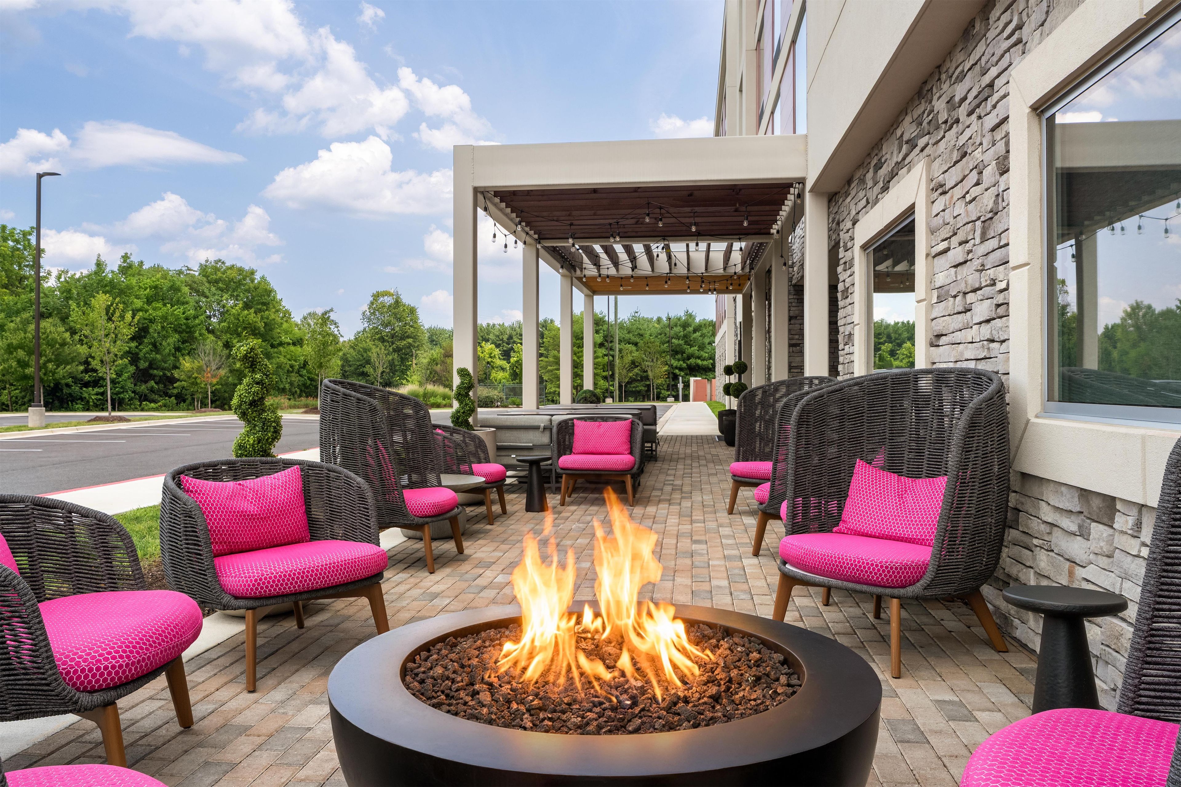 An outdoor seating area with wicker chairs and a central fire feature.