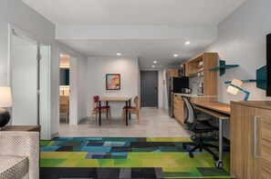 Una cocina moderna con armarios de madera, una mesa de comedor con sillas y una alfombra colorida.