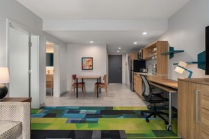 Una cocina moderna con armarios de madera, una mesa de comedor con sillas y una alfombra colorida.