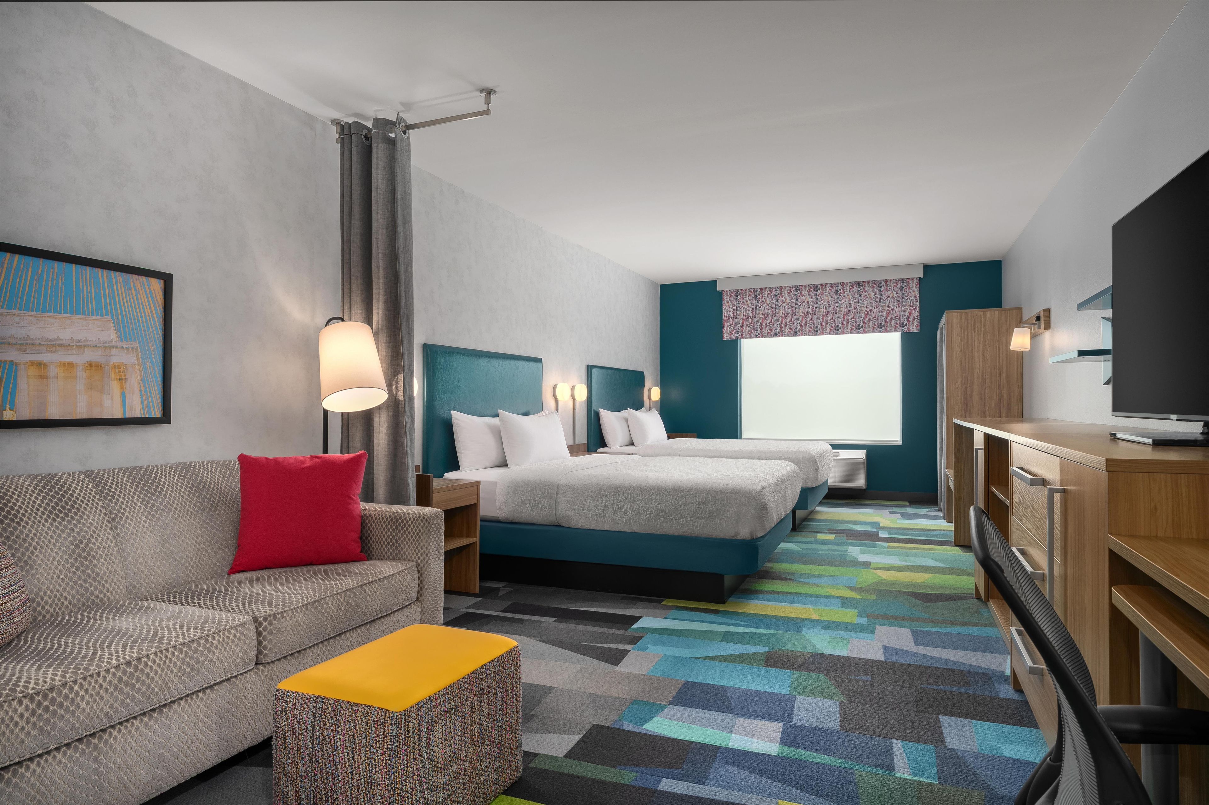 A hotel room with a sofa, a bed, a desk, and a television.