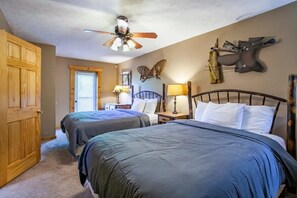 A bedroom with two beds, a ceiling fan, a wooden wardrobe, a butterfly wall decoration, and a mounted knife on the wall. - Highland View (Sevierville)