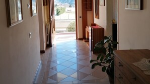 A hallway with a tiled floor leading to a balcony with a mountain view. - Residenza San Giorgio, your home in the Belluno Dolomites National Park.  (Veneto)