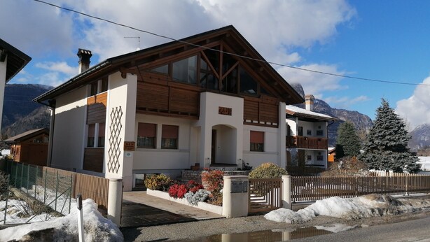 A two-story chalet with a wooden facade, large windows, and a balcony. - Residenza San Giorgio, your home in the Belluno Dolomites National Park.  (Veneto)