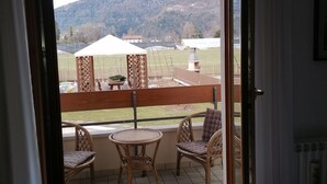 A balcony with wicker furniture and a view of a rural landscape. - Residenza San Giorgio, your home in the Belluno Dolomites National Park.  (Veneto)
