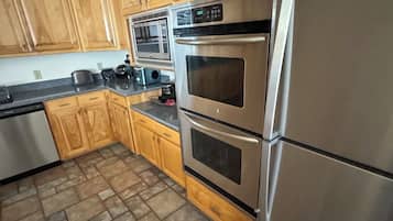 A kitchen with wooden cabinets, a stainless steel refrigerator, a microwave, and a double oven.