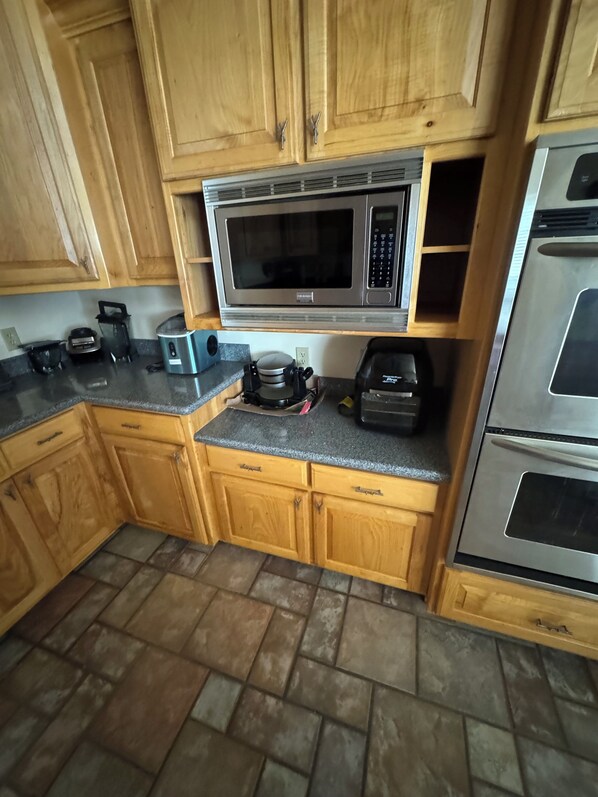 A kitchen with wooden cabinets, a microwave, a coffee maker, and an oven.