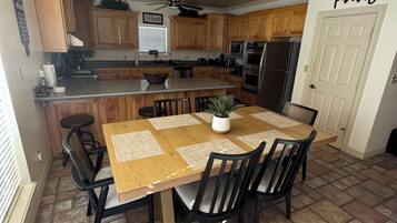 A kitchen with wooden cabinets, a central island, a dining table with chairs, and a chandelier.