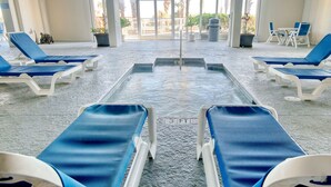 Un espace piscine comprenant des chaises longues et une piscine centrale.