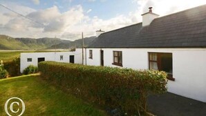 A white house with a grey roof, a chimney, and a small garden with a hedge. - Atlantic Coast (Ballyganny)