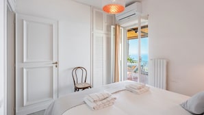 A bedroom with a bed, a chair, a window with a view, and an air conditioning unit. - Beautiful sea view with swimming pool (Massa Lubrense)