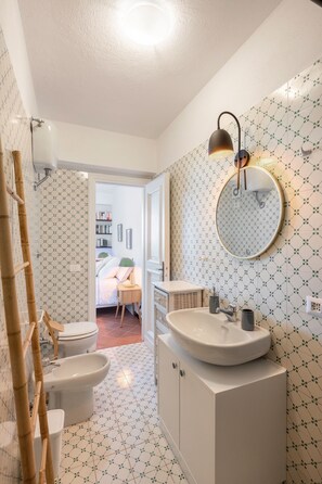 A bathroom with a white sink, a round mirror, and a toilet. - Beautiful sea view with swimming pool (Massa Lubrense)