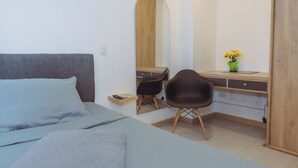 Een slaapkamer met een bed, een bureau, een stoel, een spiegel en een deur.