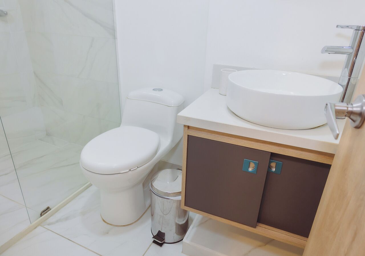 Un baño moderno con inodoro, bidé, lavamanos y mueble de almacenamiento.