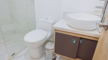 Un baño moderno con inodoro, bidé, lavamanos y mueble de almacenamiento.