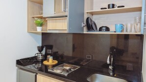 Een kleine keuken met een fornuis, spoelbak en houten kastjes.