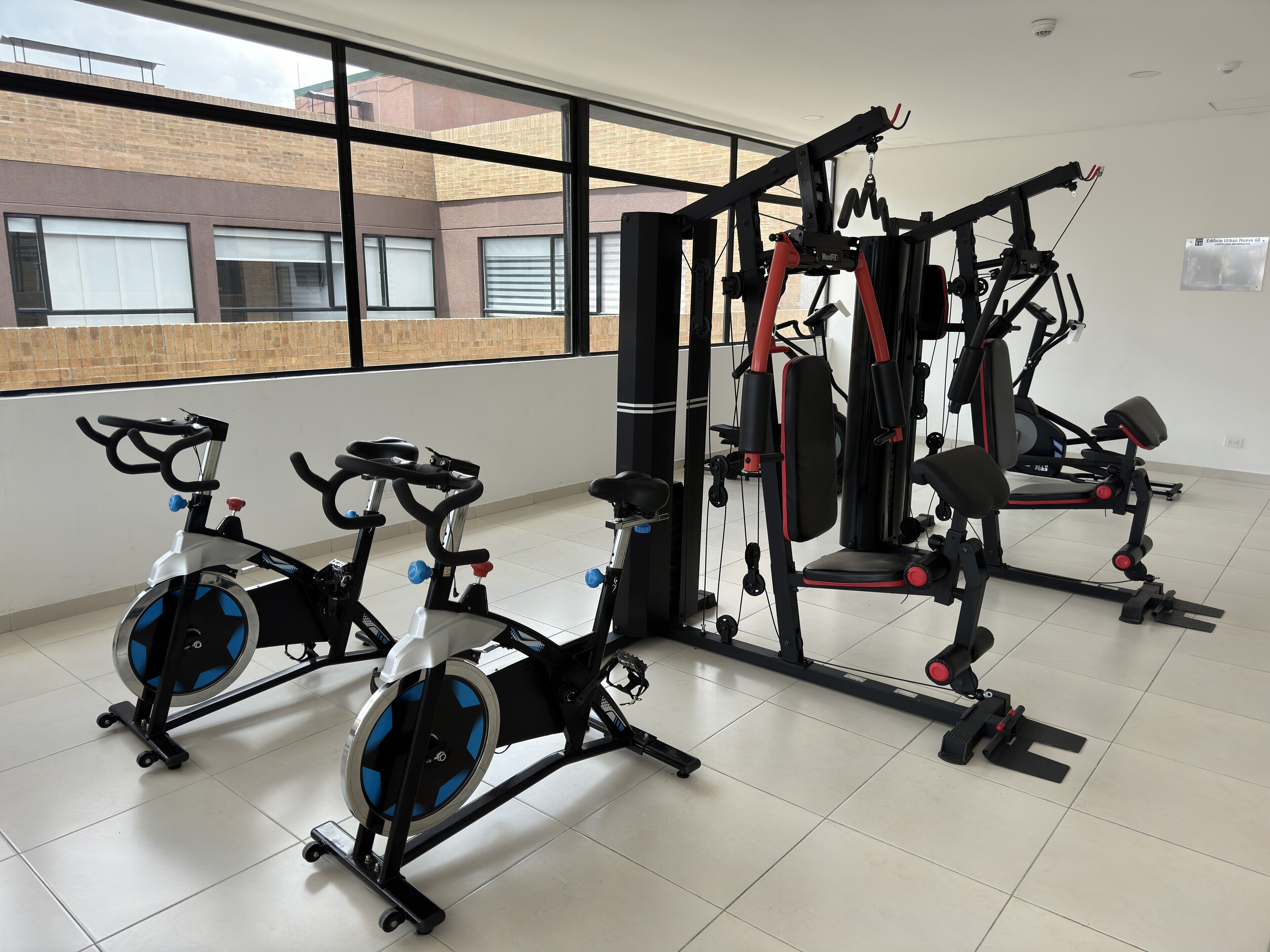 Une salle de sport équipée de vélos d’appartement, d’un banc de musculation et d’un support pour les exercices de squat.