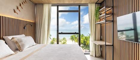 Un dormitorio moderno con una cama grande, televisión y vistas a la playa.
