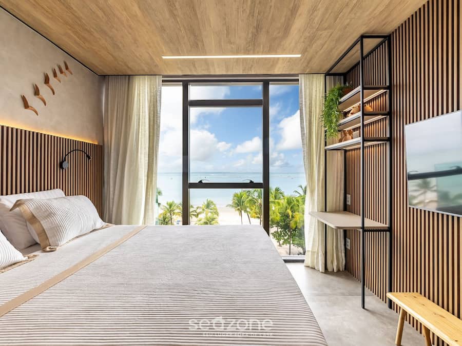 Un dormitorio moderno con una cama grande, televisión y vistas a la playa.