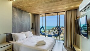 A modern hotel room with a large bed, a TV, and a view of the sea. - NWTs - Apartamentos com Vista Frente-Mar (Maceió)