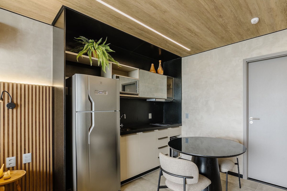 A compact kitchen with a refrigerator, microwave, and a small dining area with a table and chairs.