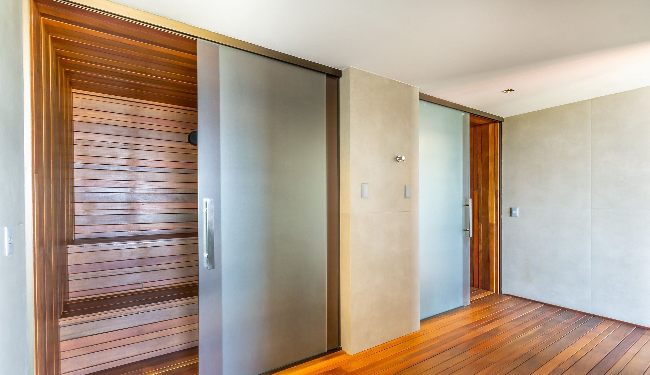 Un pasillo con puerta corredera, suelo de madera y pared de color claro.
