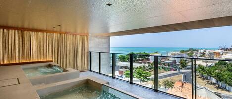 A modern indoor pool with a view of the ocean and cityscape.