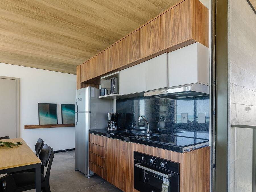 Una cocina moderna con armarios de madera, encimera negra y electrodomésticos de acero inoxidable.