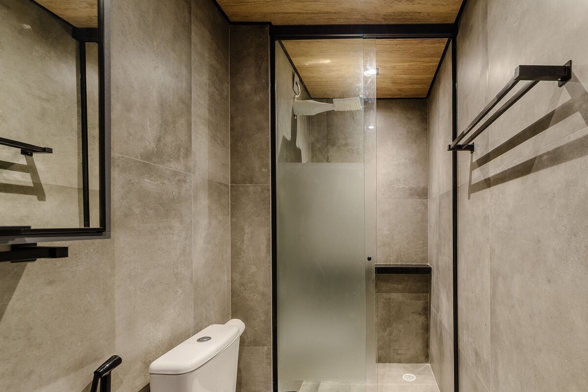Une petite cabine de douche avec une porte en verre, des toilettes et un porte-serviettes.