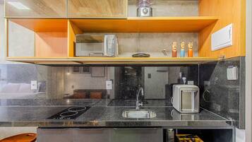 A kitchen with a black countertop, a toaster, a sink, and a microwave.