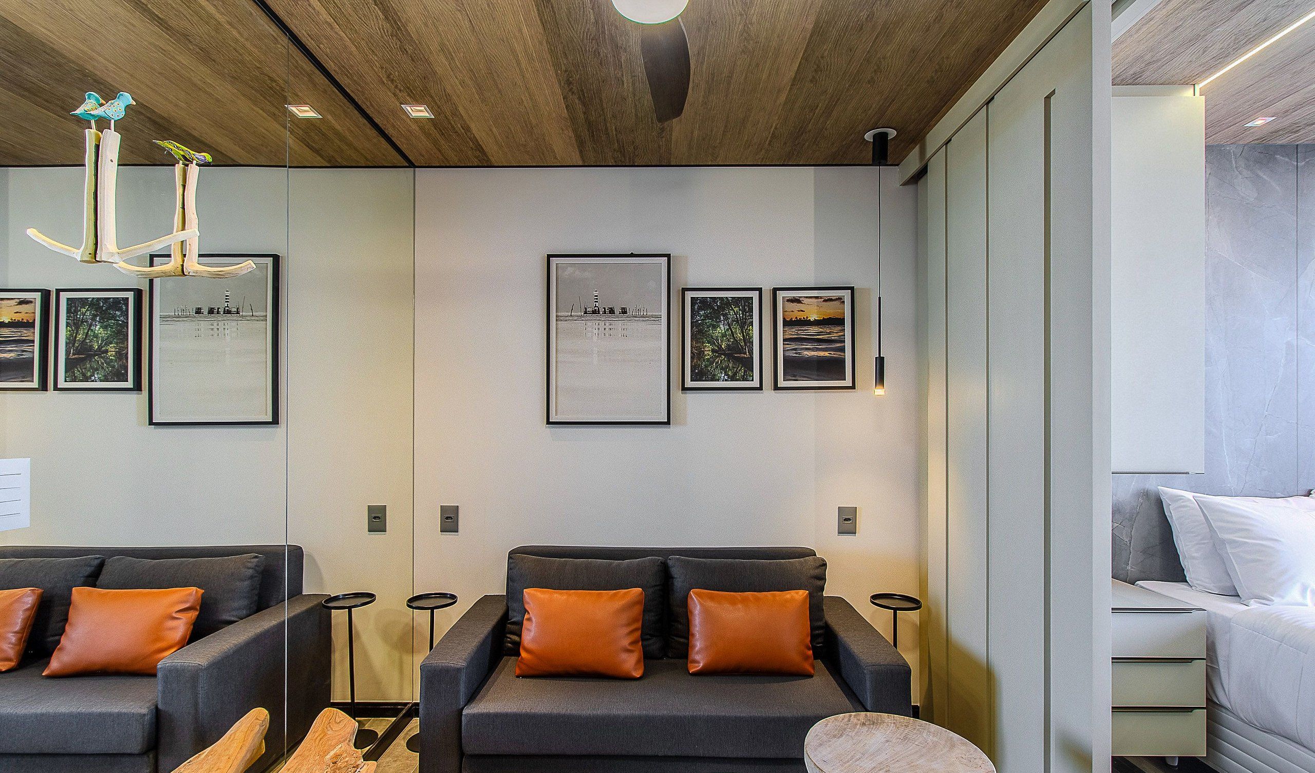 A modern hotel room with a sofa set, a bed, and framed pictures on the wall.