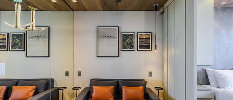 A modern hotel room with a sofa set, a bed, and framed pictures on the wall.