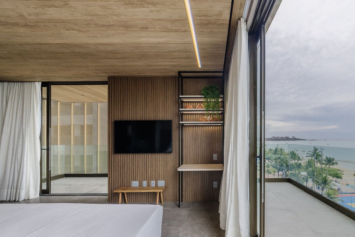 Une chambre d’hôtel moderne dotée d’un grand balcon, d’une télévision à écran plat et offrant une vue sur la plage.